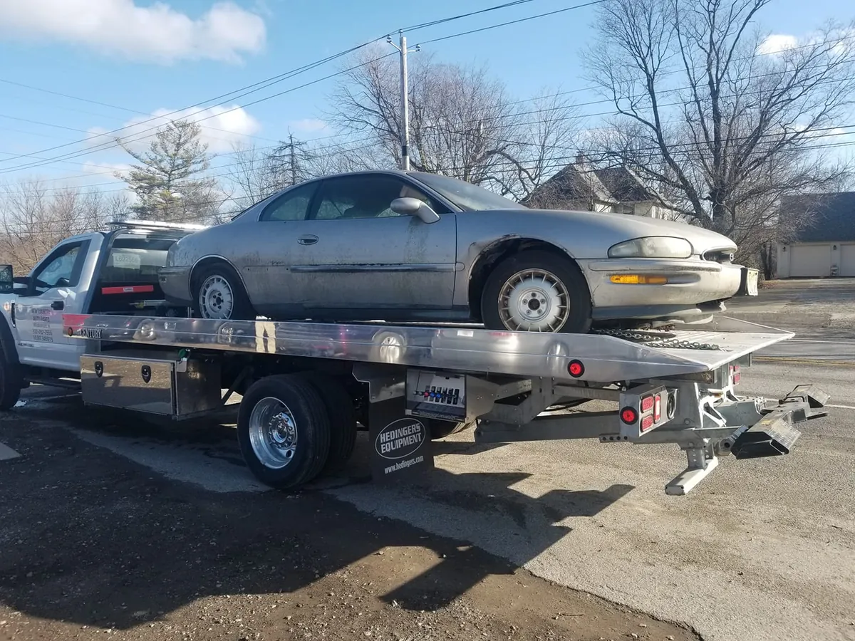 New Country Auto flatbed tow truck picking up a white sedan for Cash Car Heroes