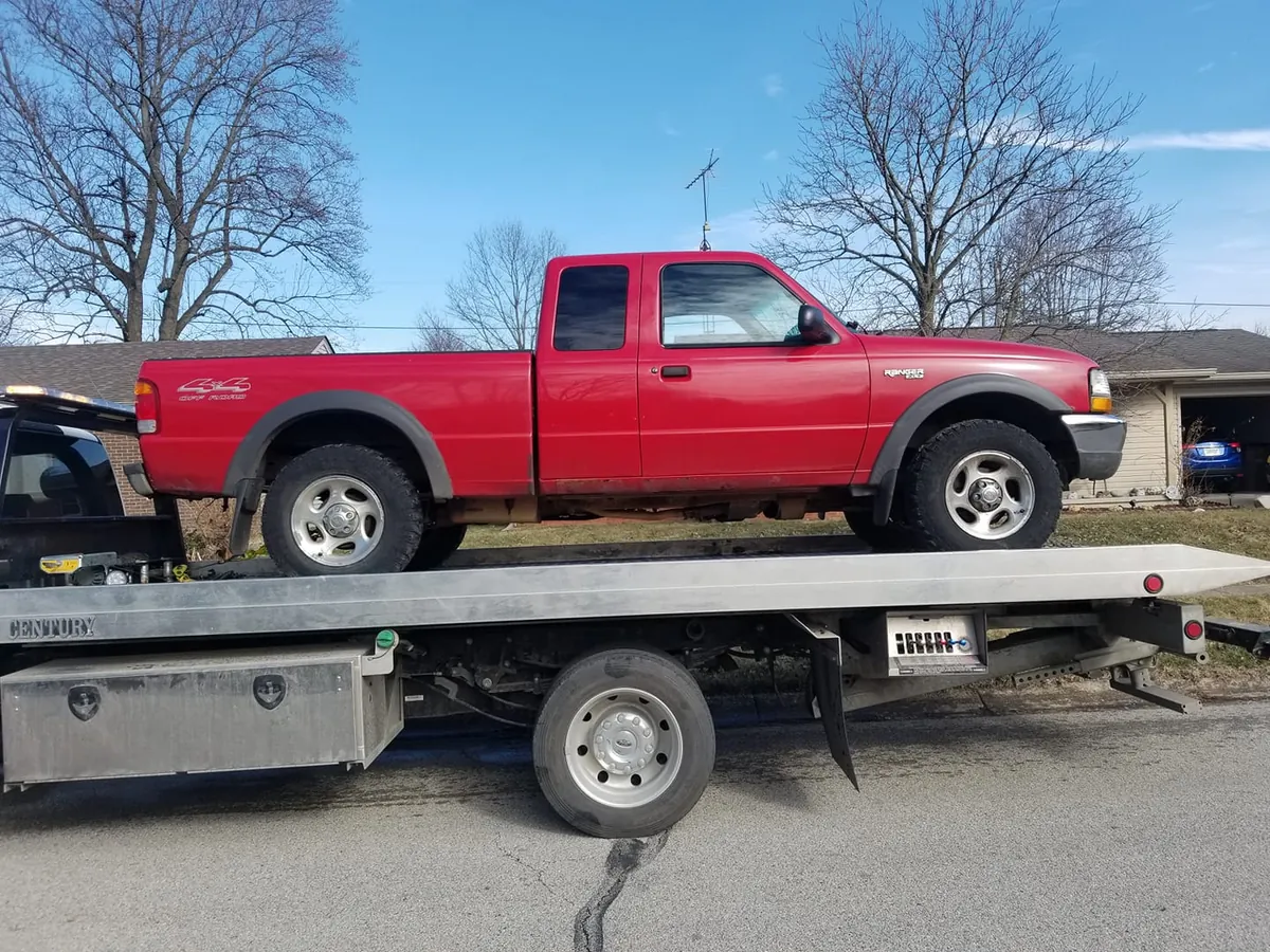 Red Ford Ranger pickup truck with visible wear being evaluated for a cash offer